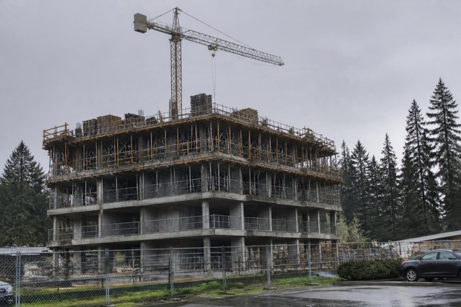 Mid-rise concrete building with slab formwork on the upper floors and a tower crane
